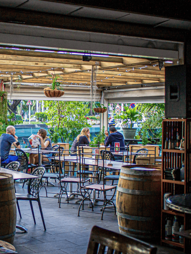 Outdoor restaurant patio with patrons, greenery, and ambient lighting, perfect for dining and socializing.