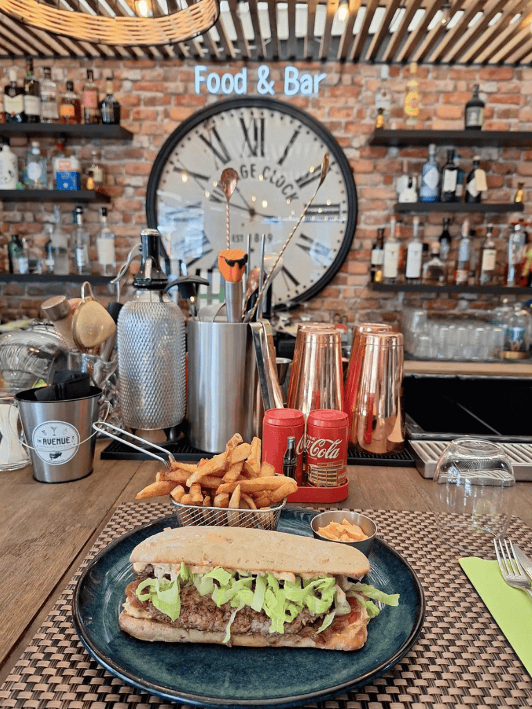 Fresh cheesesteak sandwich with lettuce and a side of fries at a trendy bar and restaurant.