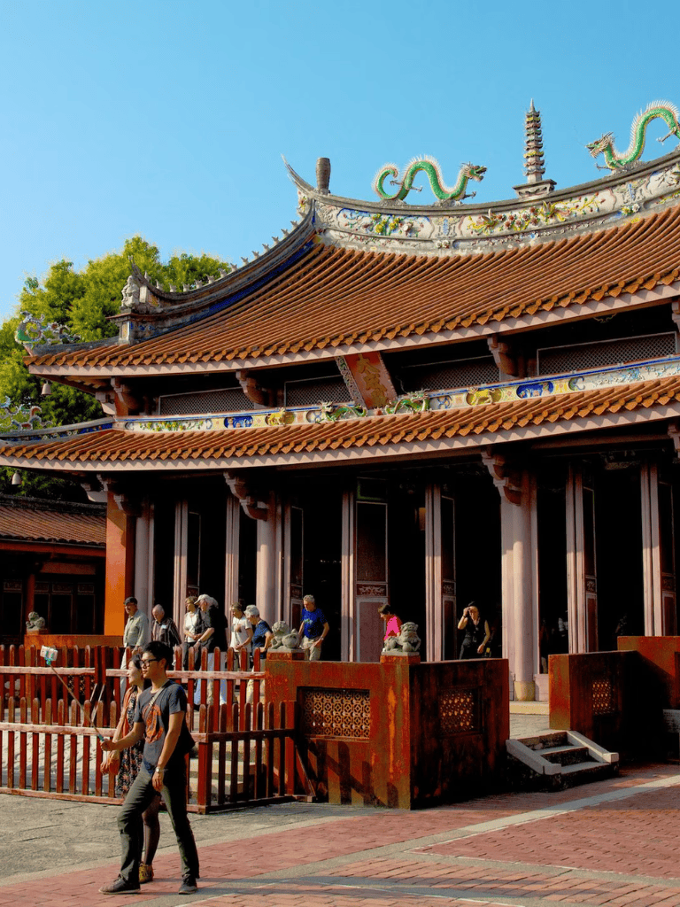 Vibrant traditional Chinese temple with ornate roof, colorful dragons, and visitors exploring temple grounds.