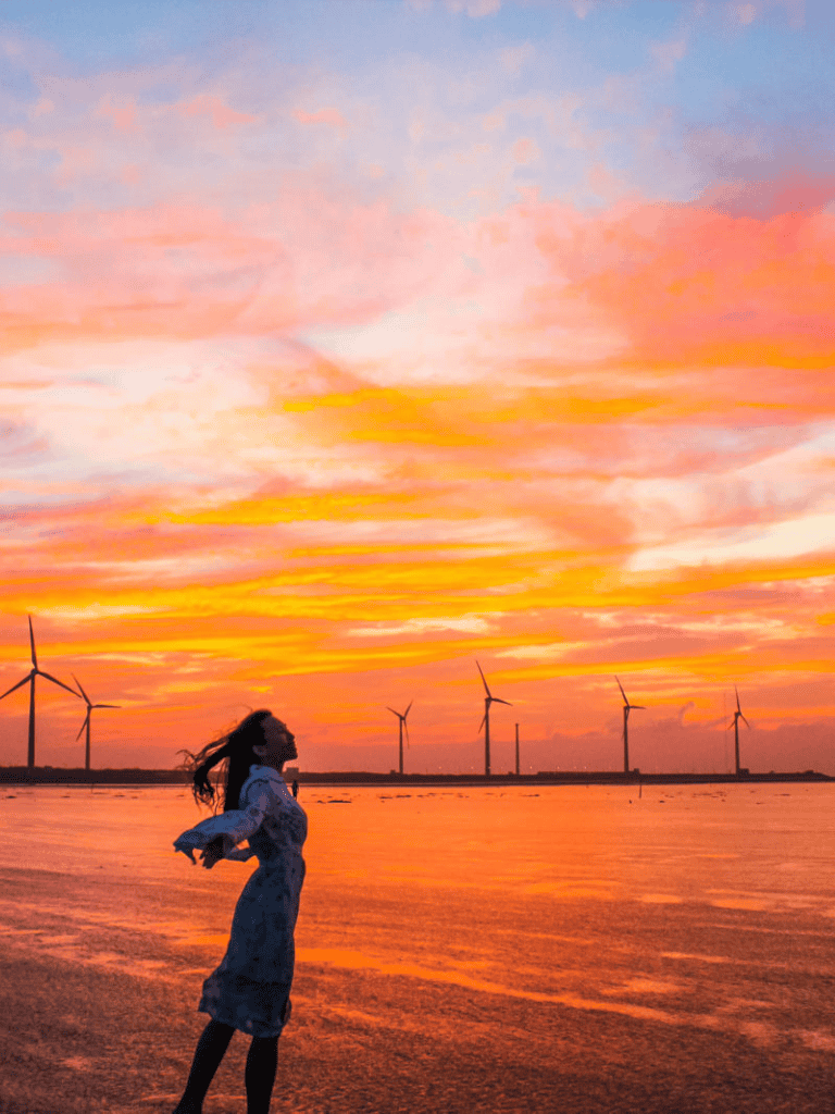 Vast sunset over wind turbines with woman enjoying scenic outdoor view at QuestForDirections.