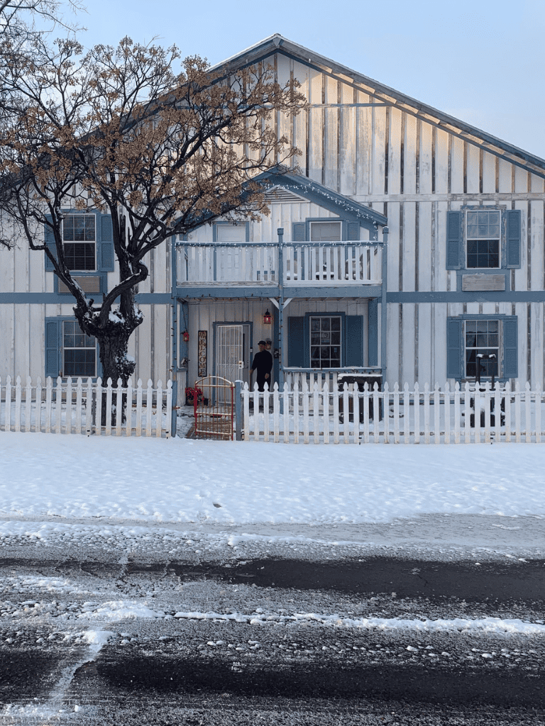 Cozy winter house with white picket fence and snow-covered yard, perfect for cozy home searches.