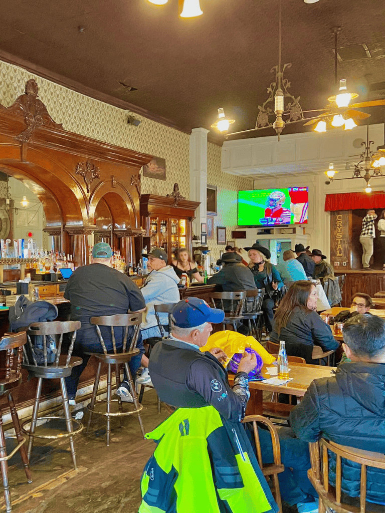 Cozy pub interior with group of people enjoying drinks and watching sports on TV.