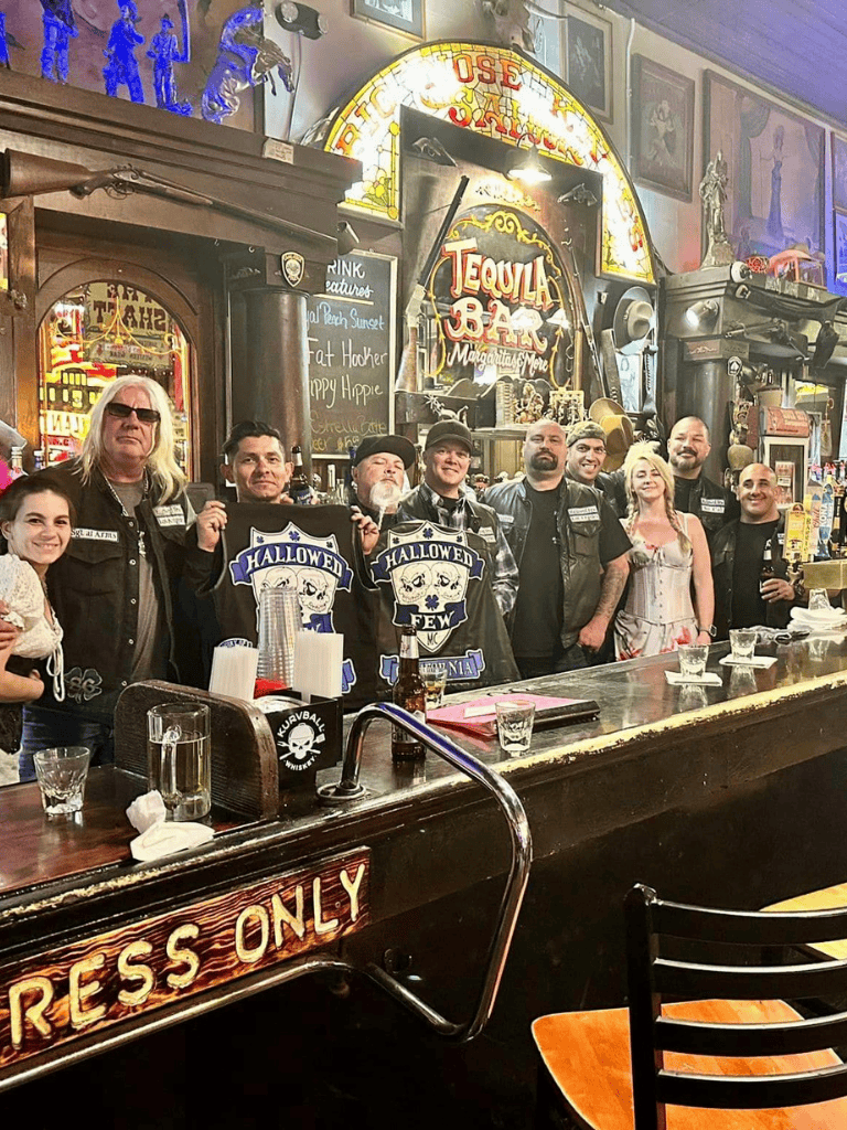Vintage bar scene with people celebrating Halloween, lively atmosphere, decorated with neon signs and retro decor.