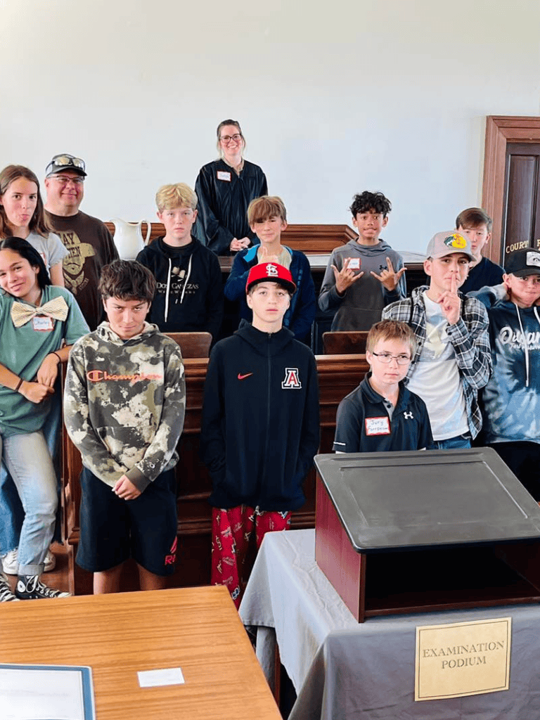 Inspiring group of children and teens attending a mock court or school event at the Examination Podium, promoting education and community engagement.