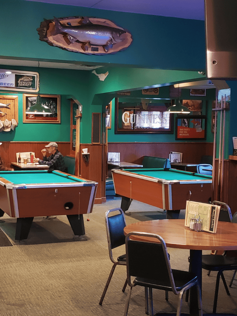 A cozy bar with pool tables, nautical decor, and casual seating, perfect for relaxed social gatherings and sports viewing.