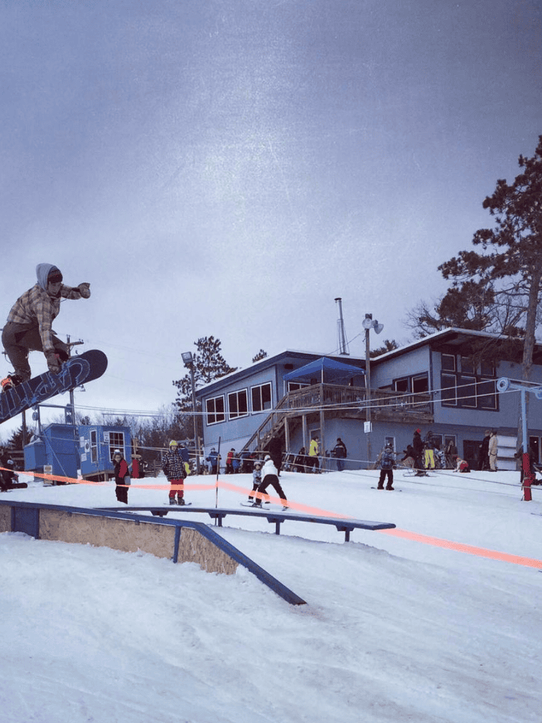 Skateboarder performing tricks at QuestForDirections snowboarding resort in winter.