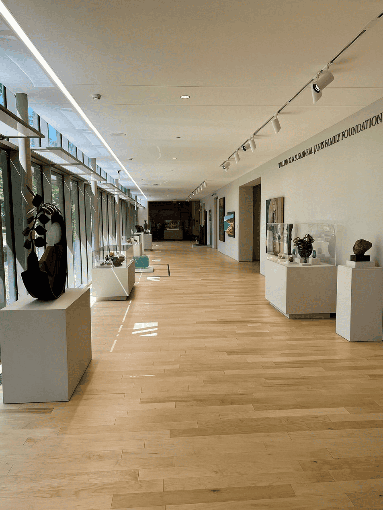Modern art gallery interior with sculptures and paintings, featuring natural light and sleek design.