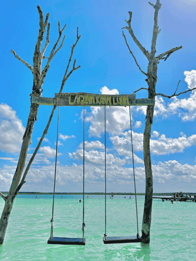 Swings hanging over clear turquoise water at Lagoon Key Lush with blue sky.