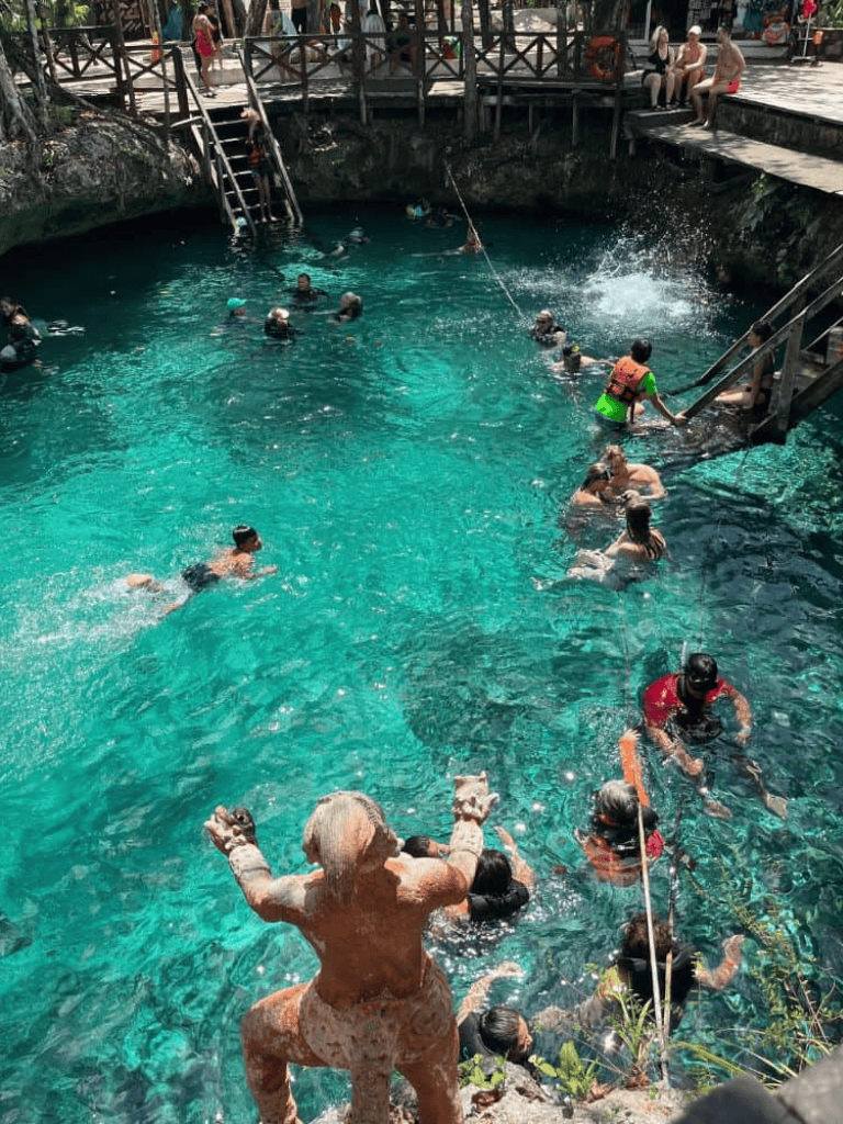 Children swimming in a natural hot spring pool with wooden dock and scenic surroundings.