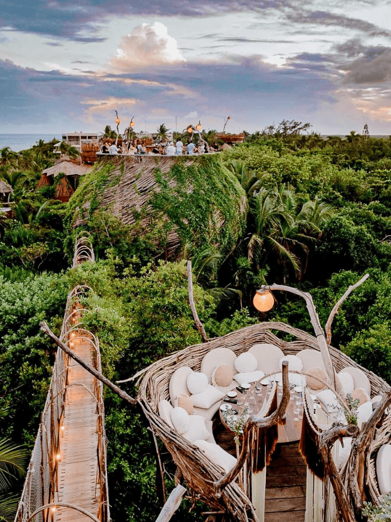 Vibrant outdoor event venue surrounded by lush greenery and treehouse-style structures for unique celebrations.