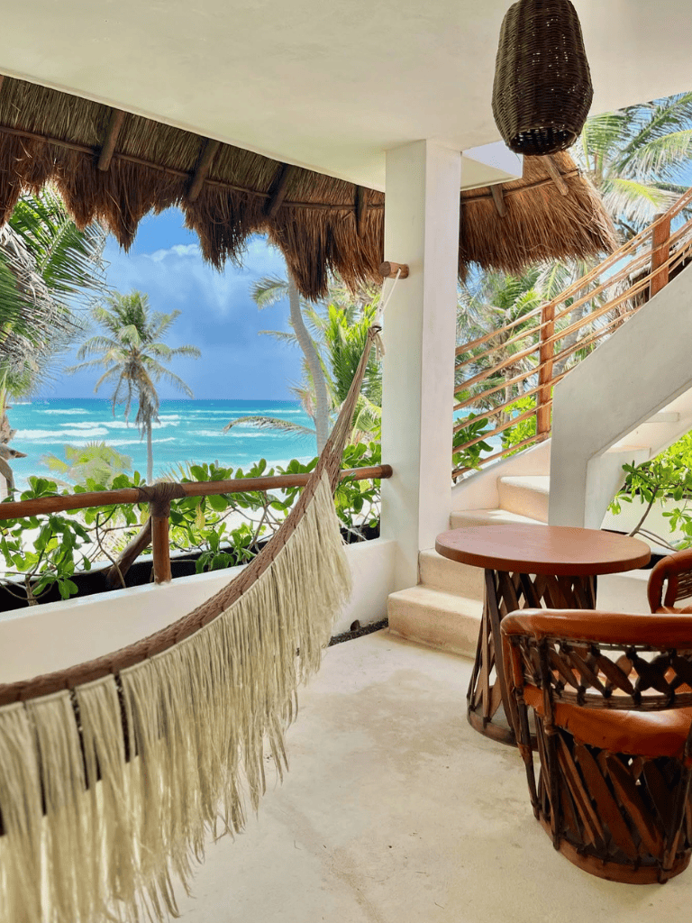 Relaxing beachfront balcony with hammock, tropical views, and outdoor seating at a Caribbean resort.
