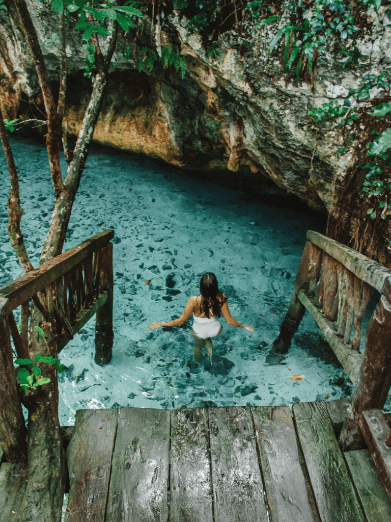 Serene woman swimming in clear water at Jungle River, surrounded by lush greenery and rocky cliffs.