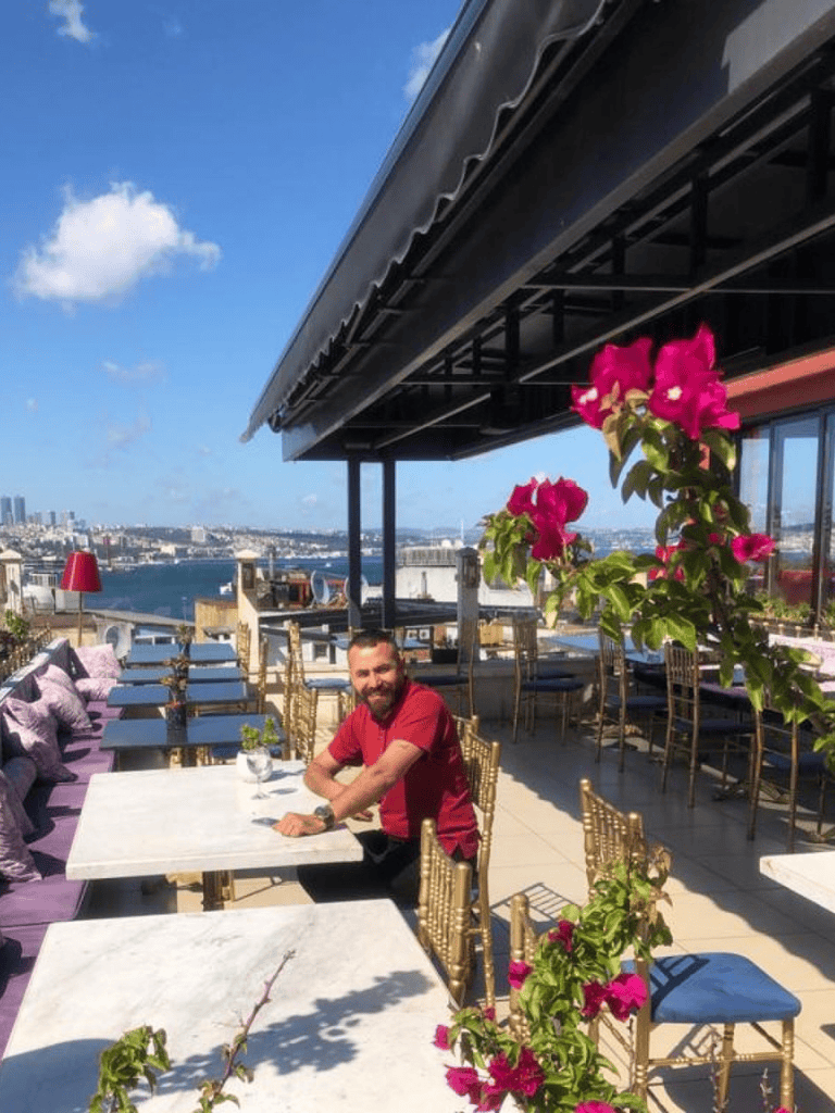 Vibrant rooftop restaurant with city skyline views and lush pink bougainvillea, perfect for dining and leisure.
