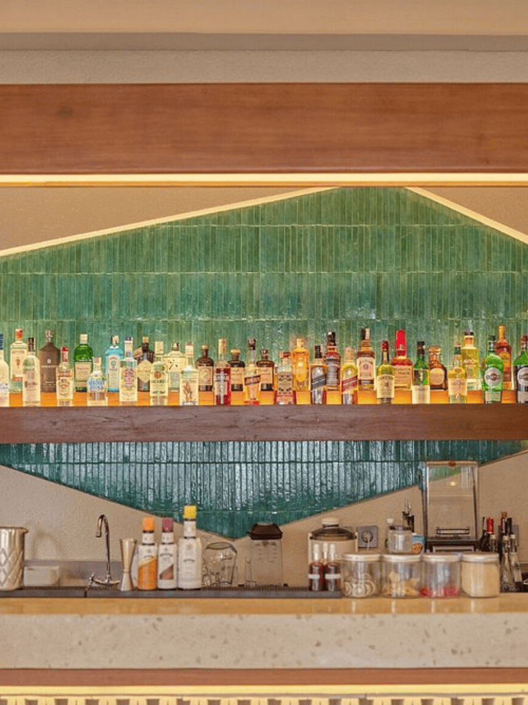 A wide selection of alcoholic beverages displayed behind a bar for quests and travelers.