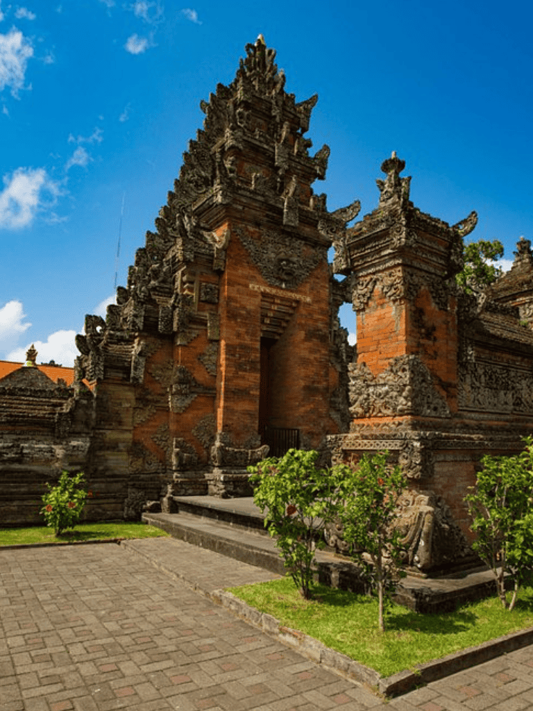 Ancient Balinese temple gate with intricate carvings and lush surroundings.