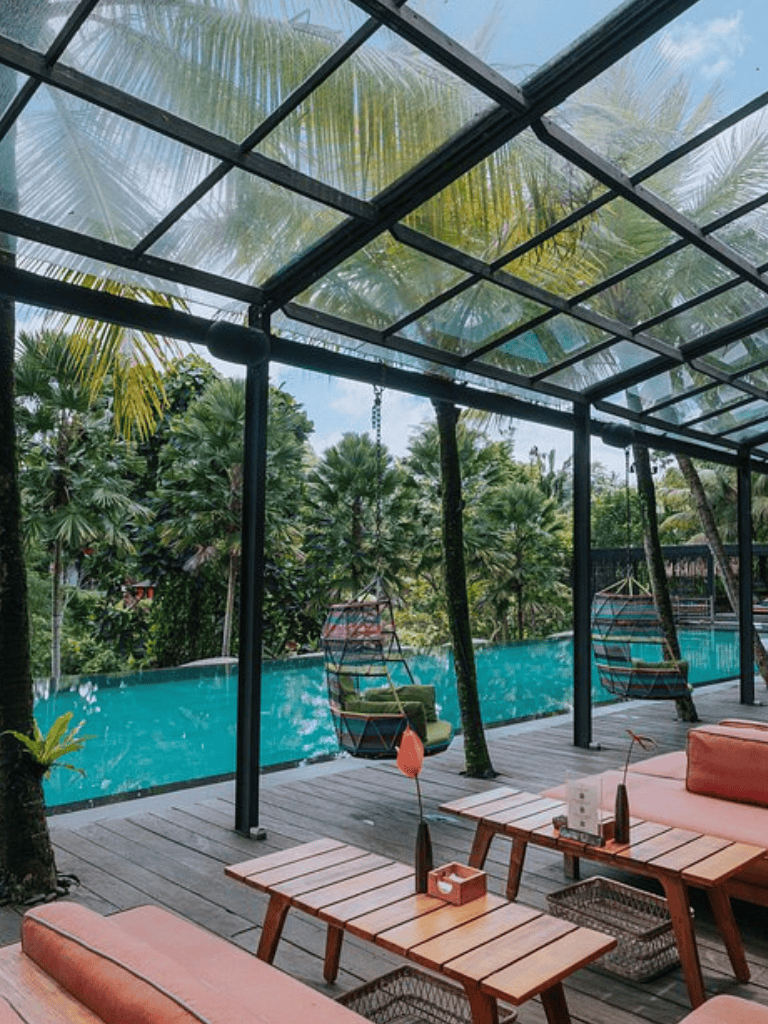 Relaxing tropical poolside lounge with glass roof, lush greenery, and modern seating at QuestForDirections.