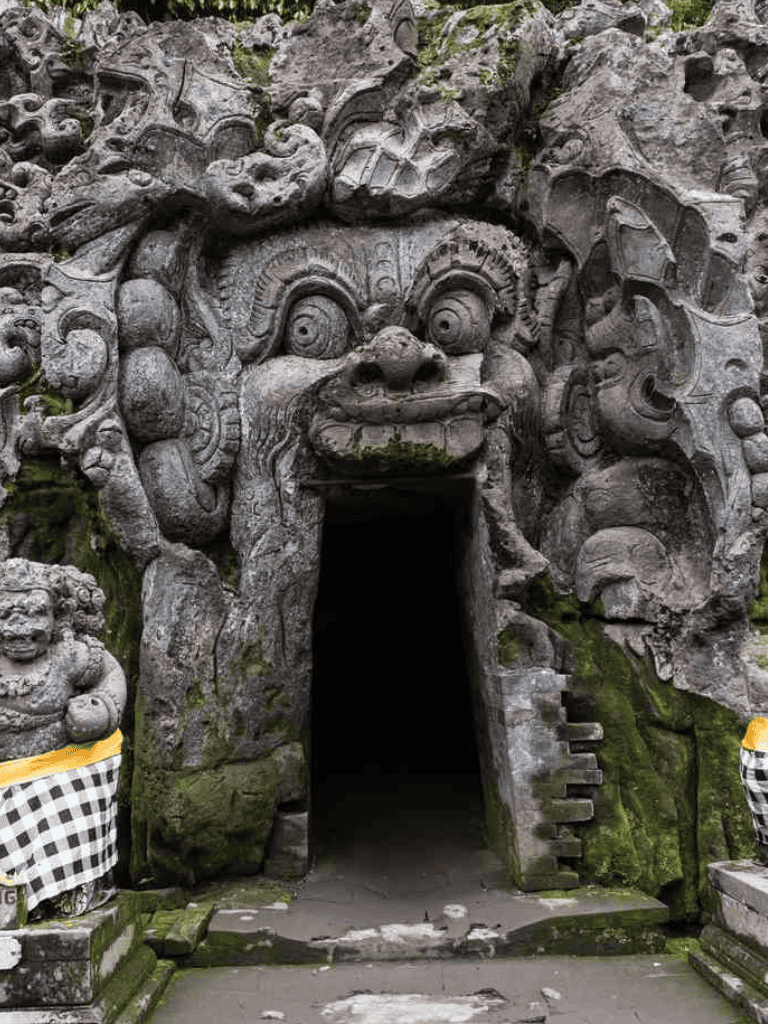 Intricate stone carvings of a mythical creature's face forming a temple entrance, popular in Indonesian culture.