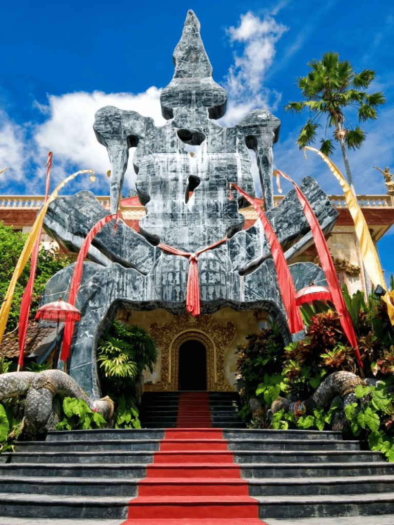 Majestic dragon sculpture entrance at Vietnamese temple with lush greenery and vibrant red carpet.
