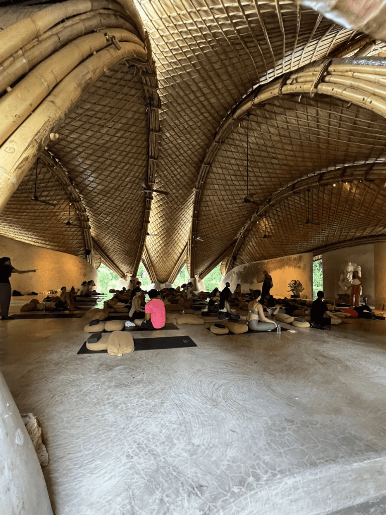 Serene yoga class inside bamboo structure, tropical wellness retreat and relaxation space.