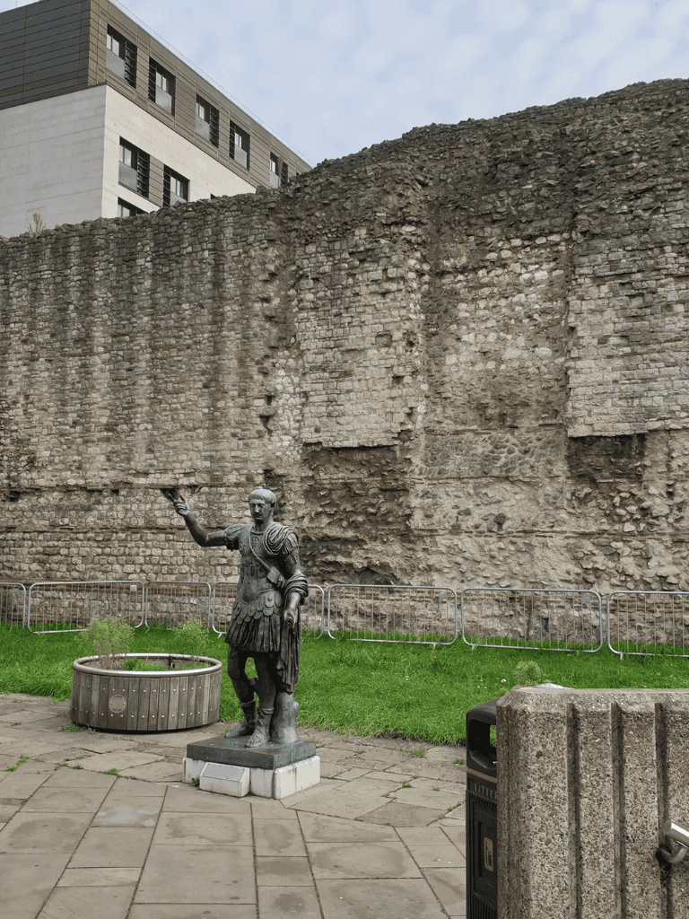 Brutus statue in Roman forum with modern buildings in the background, historical monument, and tourist attraction in Rome.