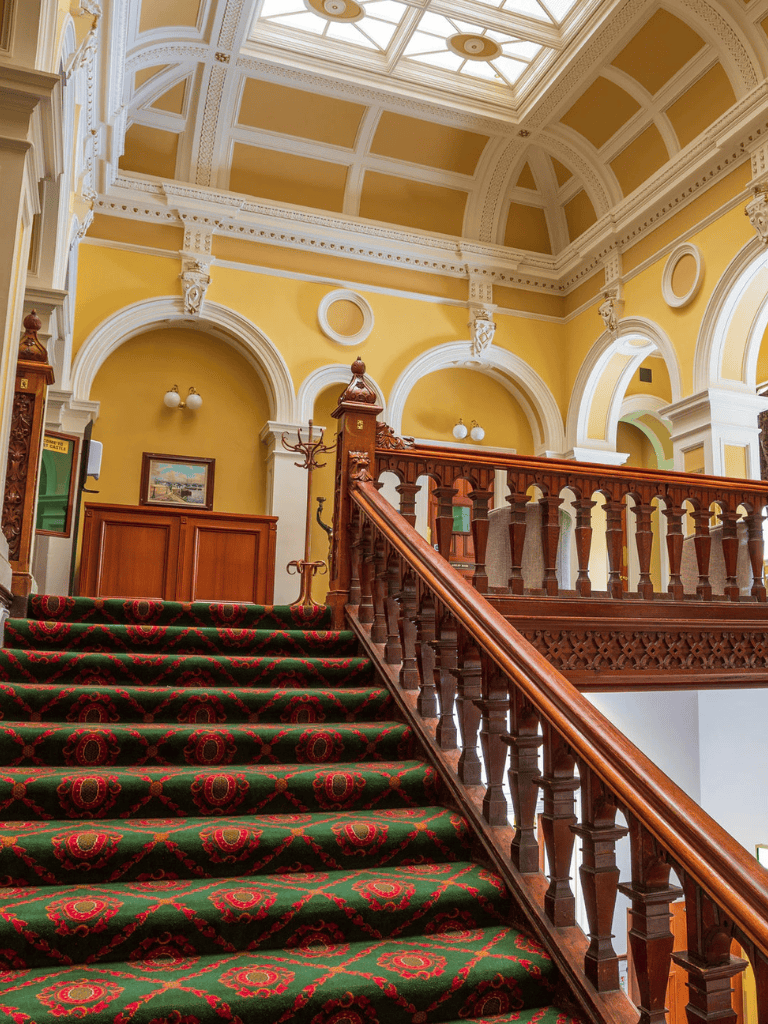 Luxurious historic interior of Quest for Directions building with ornate staircase and decorative architectural details.