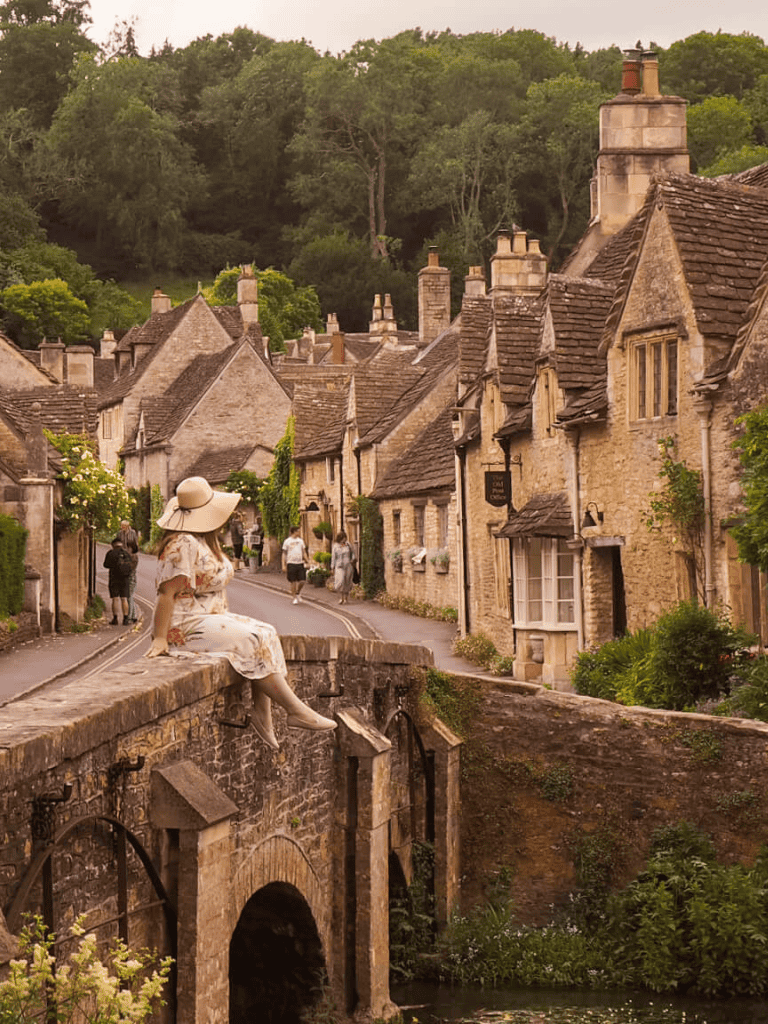 Charming historic village in Cotswolds with stone cottages and lush greenery.