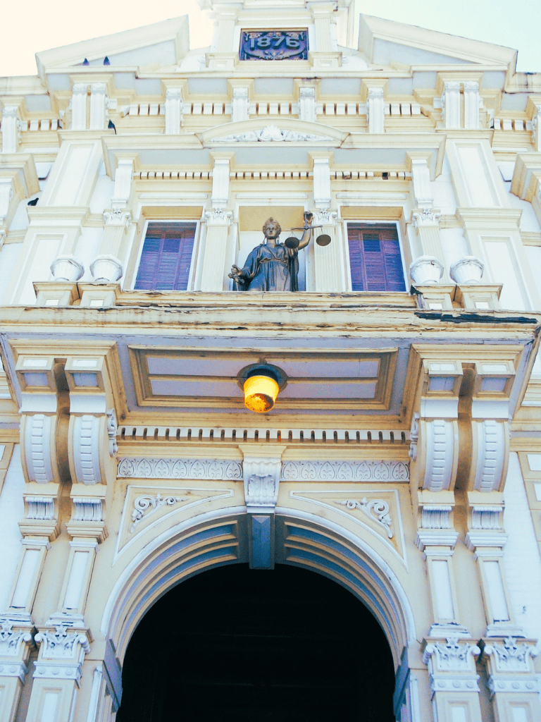 Statue of Lady Justice on historic courthouse facade with ornate architectural details and decorative columns.