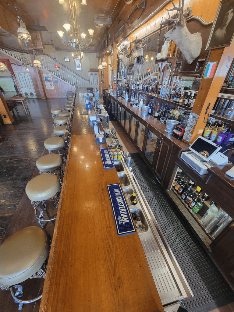Bar interior with wooden countertops and mounted deer heads, cozy ambiance with vintage decor.