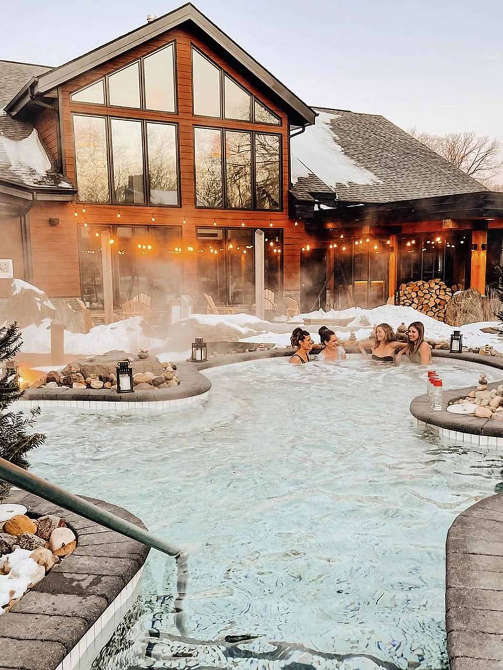 Outdoor hot tub with relaxing steam, cozy wooden house, winter snow, and friends enjoying hot water, perfect for a winter getaway.