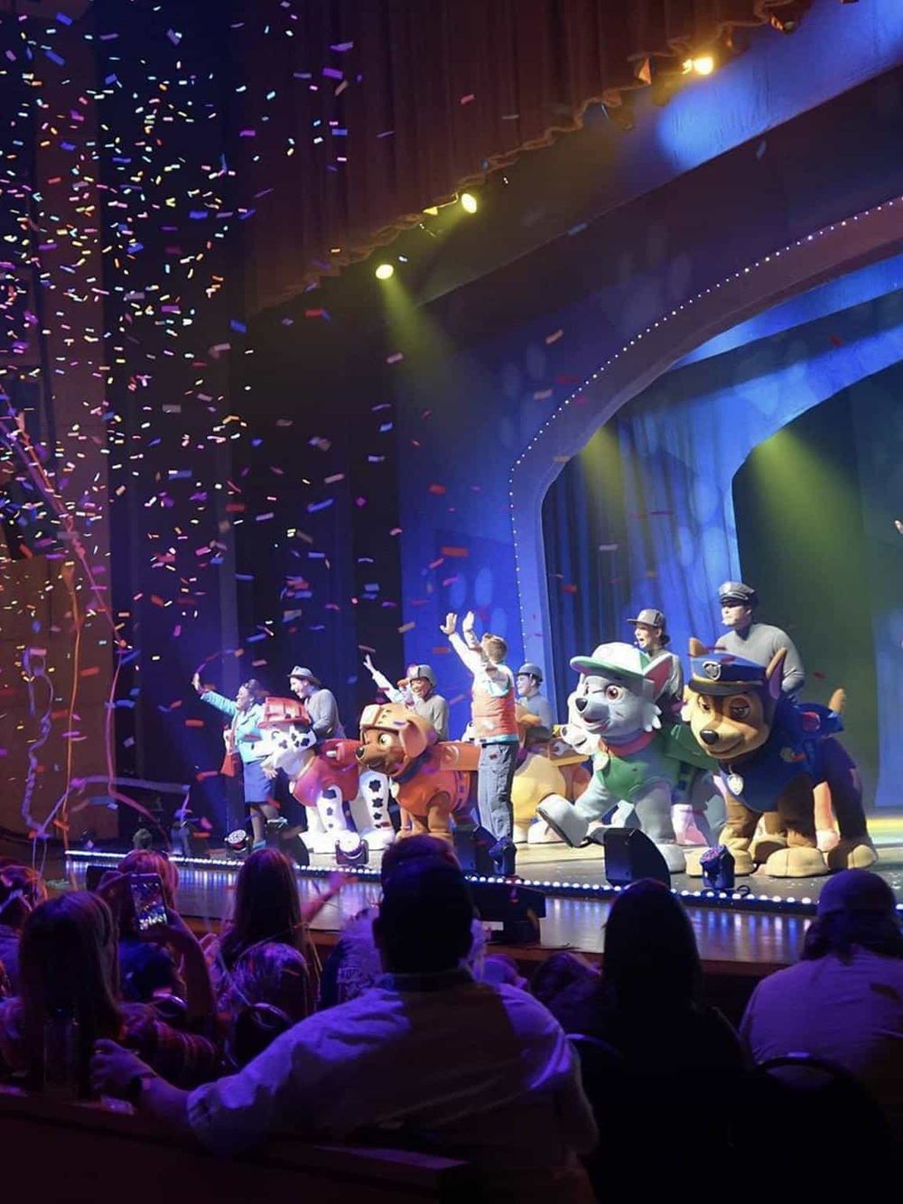 Colorful stage performance featuring PAW Patrol characters with audience enjoying the show.