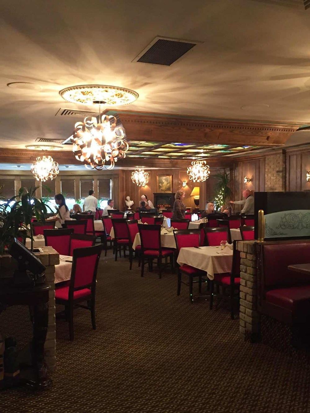 Elegant restaurant interior with warm lighting and red upholstered chairs.