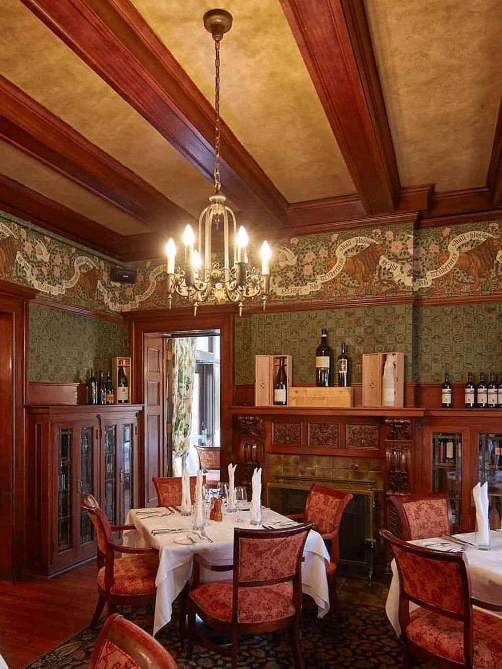 Elegant dining room featuring vintage wood paneling, ornate chandelier, and classic table settings.