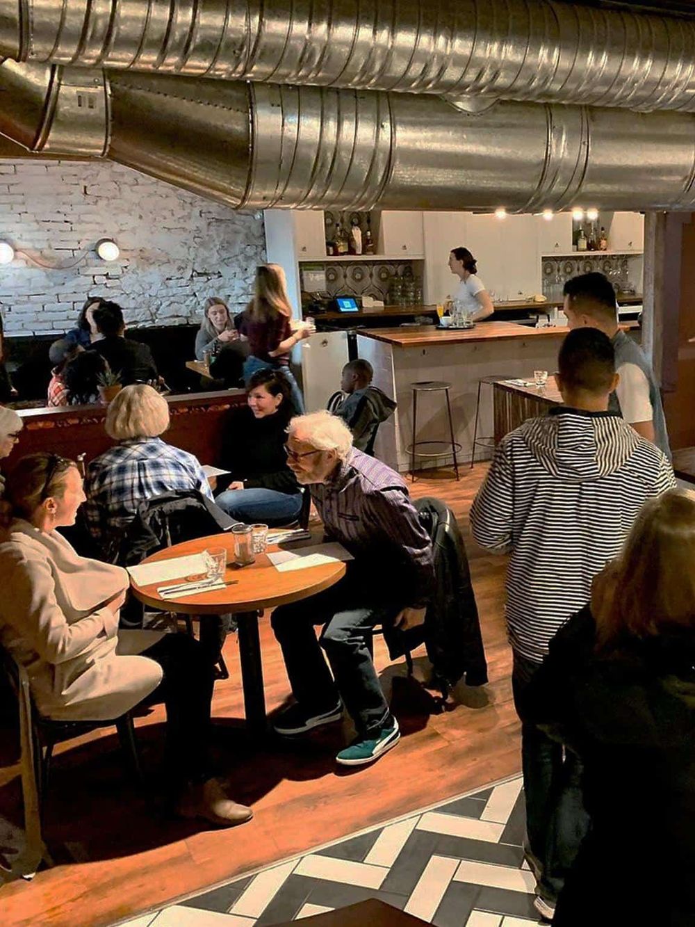 Cozy restaurant interior with diverse group dining, modern decor, and friendly atmosphere, perfect for social gatherings.