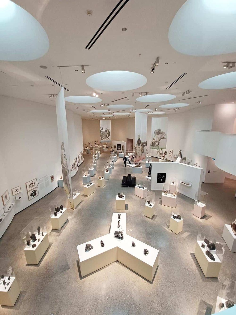 Modern art gallery showcasing diverse sculptures and artwork in a spacious, well-lit interior.