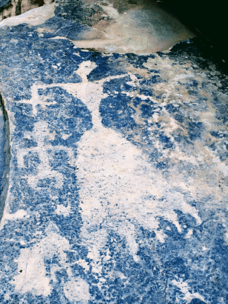 Ancient petroglyph of a cross and figures on rock surface, historical indigenous rock art.