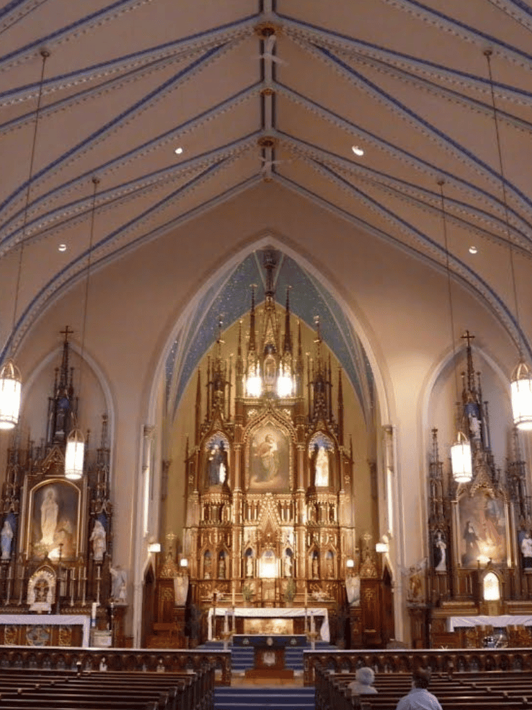 Intricate church altar with ornate woodwork, religious statues, and dramatic lighting in a historic Catholic church.