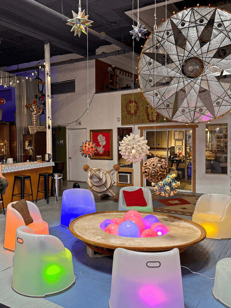 Colorful modern decor with hanging art installations and illuminated chairs.