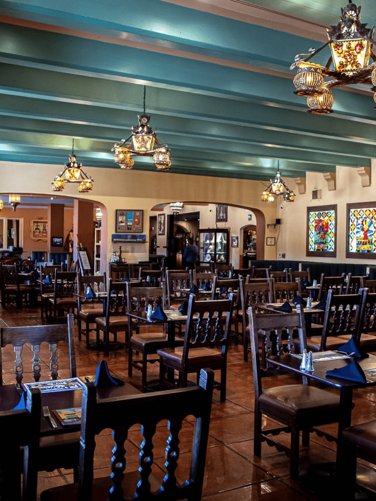 Colorful restaurant interior with wooden tables and chairs, stained glass windows, and vibrant hanging lanterns.