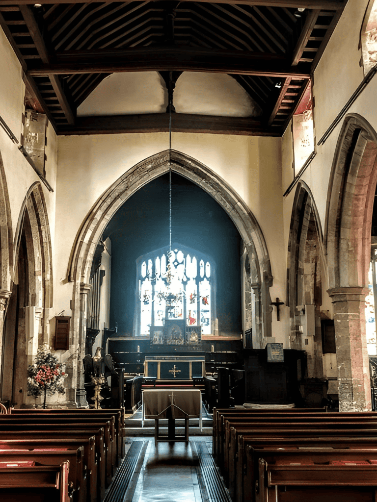 Victorian church interior with altar, stained glass window, and wooden pews, showcasing historic architecture and religious art.