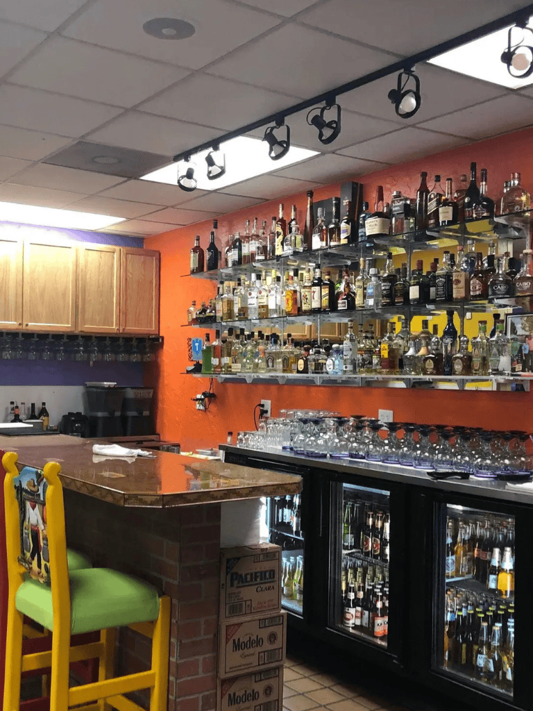 1. Well-stocked bar with liquor bottles, glassware, and colorful decor at QuestForDirections.