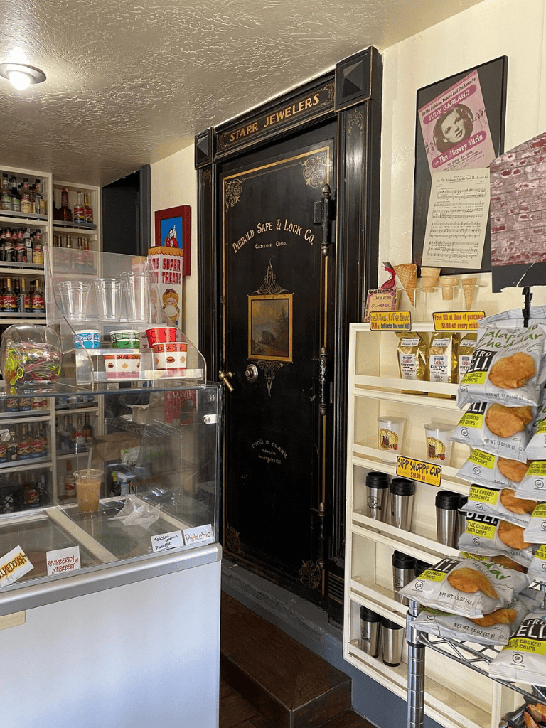 Vintage jewelry shop interior with dark ornate safe and snack display.