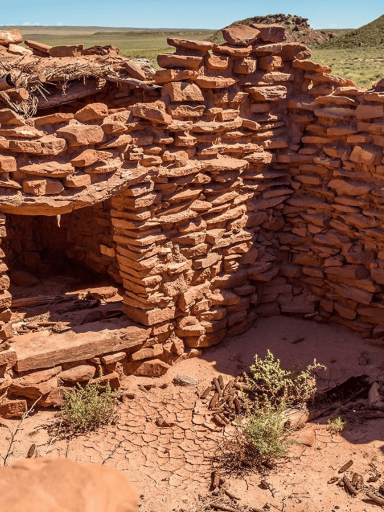 Stacked red stone ruins in desert landscape, archaeological site, historic indigenous dwelling or shelter.