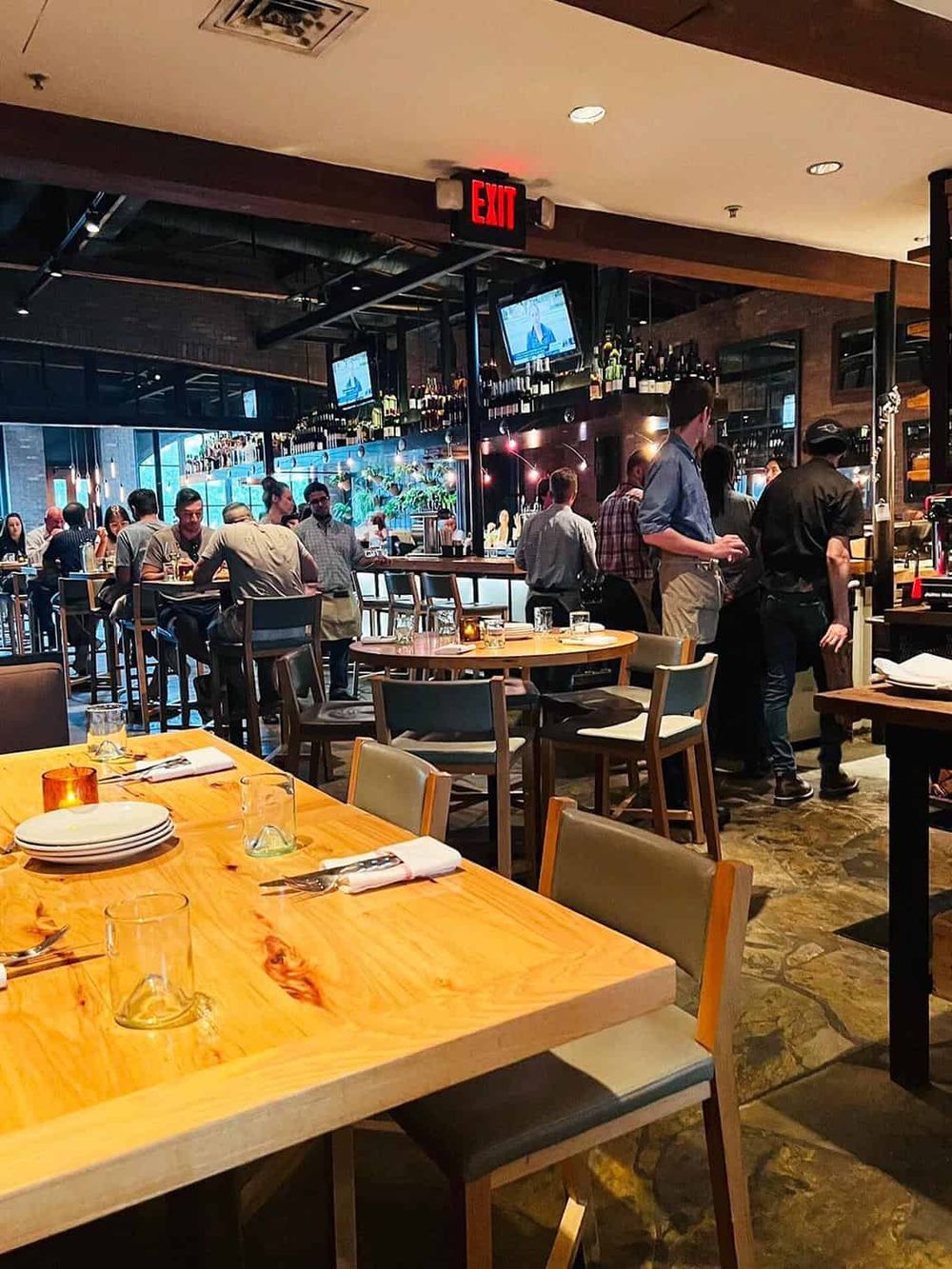 Cozy modern restaurant interior with bar, dining tables, and customers enjoying meals. Perfect for dining out or casual gatherings.