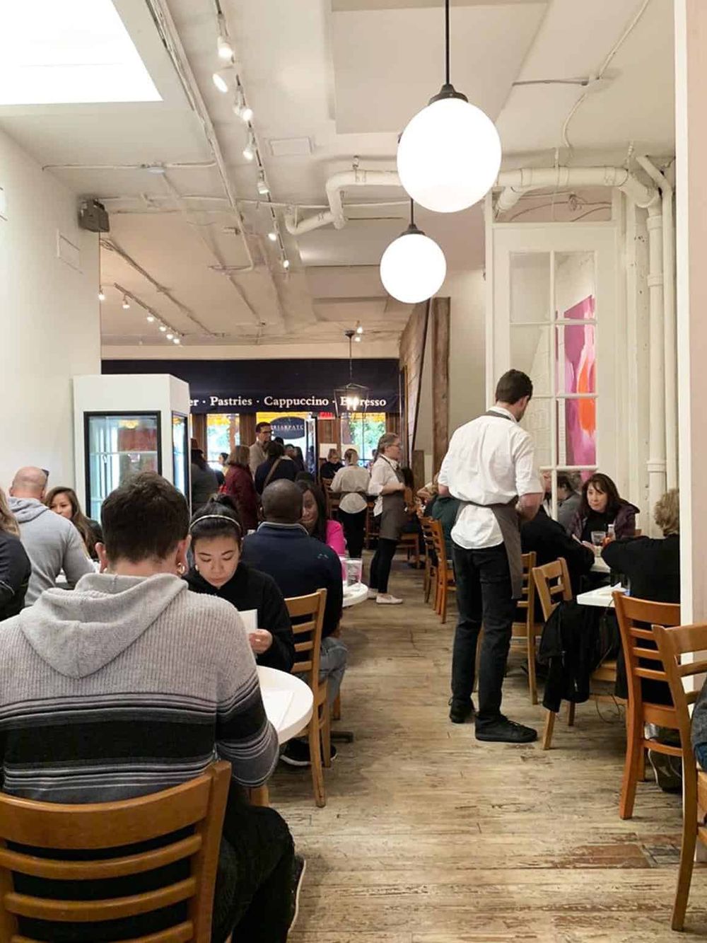 Cozy café interior with diners enjoying meals, modern lighting, and a welcoming atmosphere for coffee and pastries.