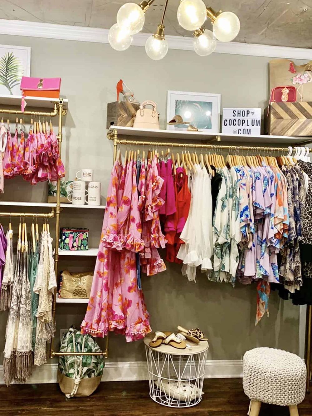 Colorful boutique clothing display with pink, red, and floral outfits in a trendy store.