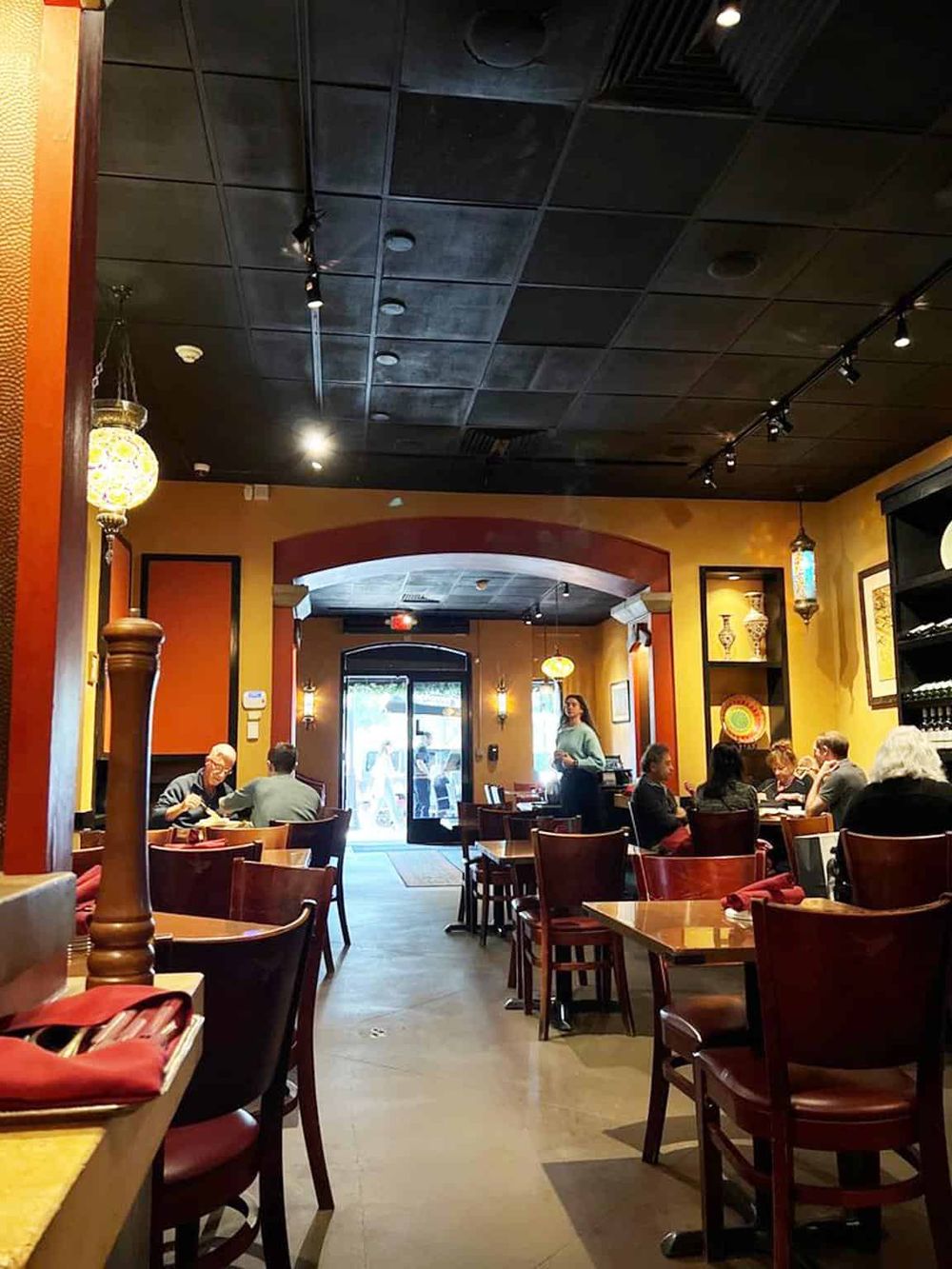 Cozy restaurant interior with warm lighting, wooden furniture, and diverse patrons enjoying meals.