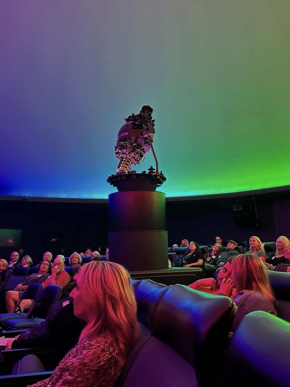 Colorful planetarium theater with audience watching a STEM presentation on space exploration.