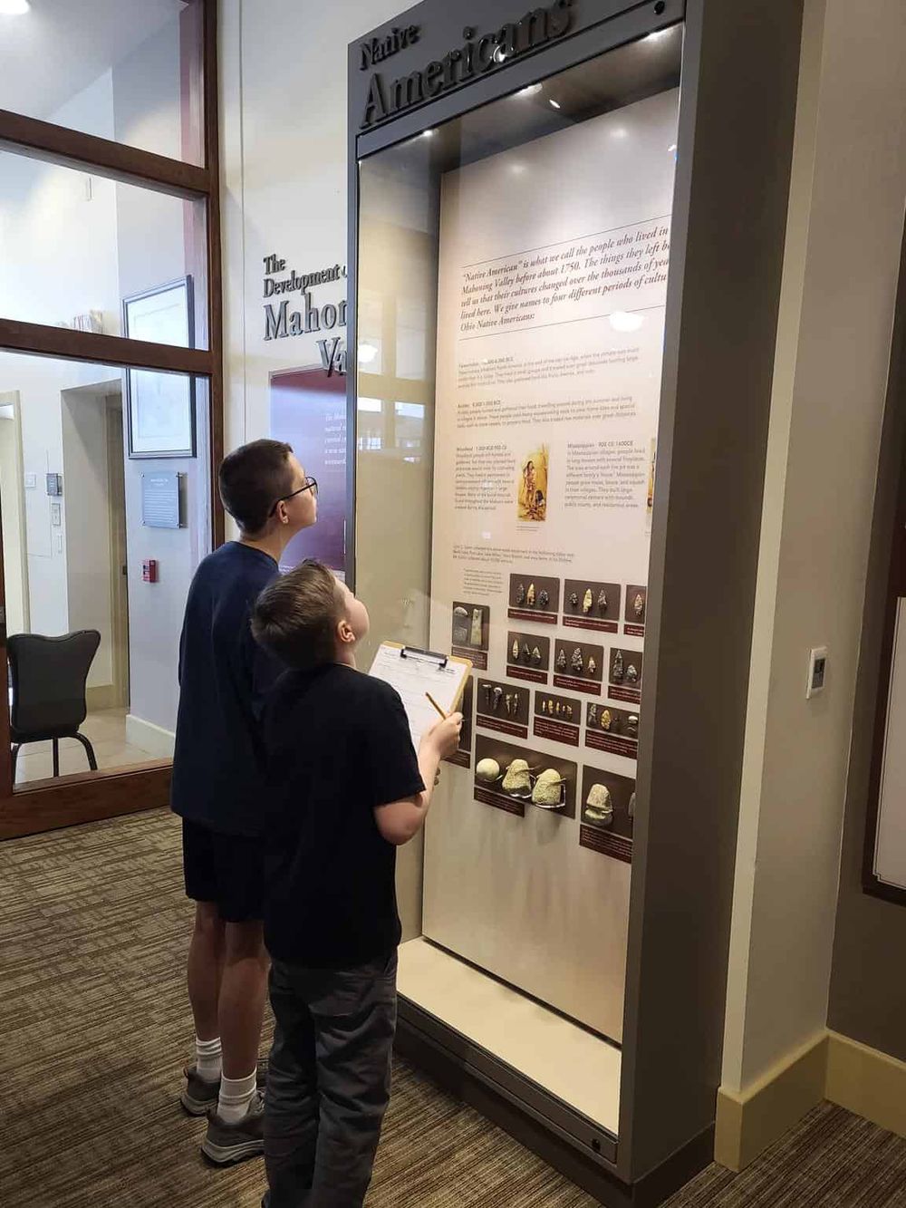 Ancient artifact display at a museum with children viewing historical relics and information boards.