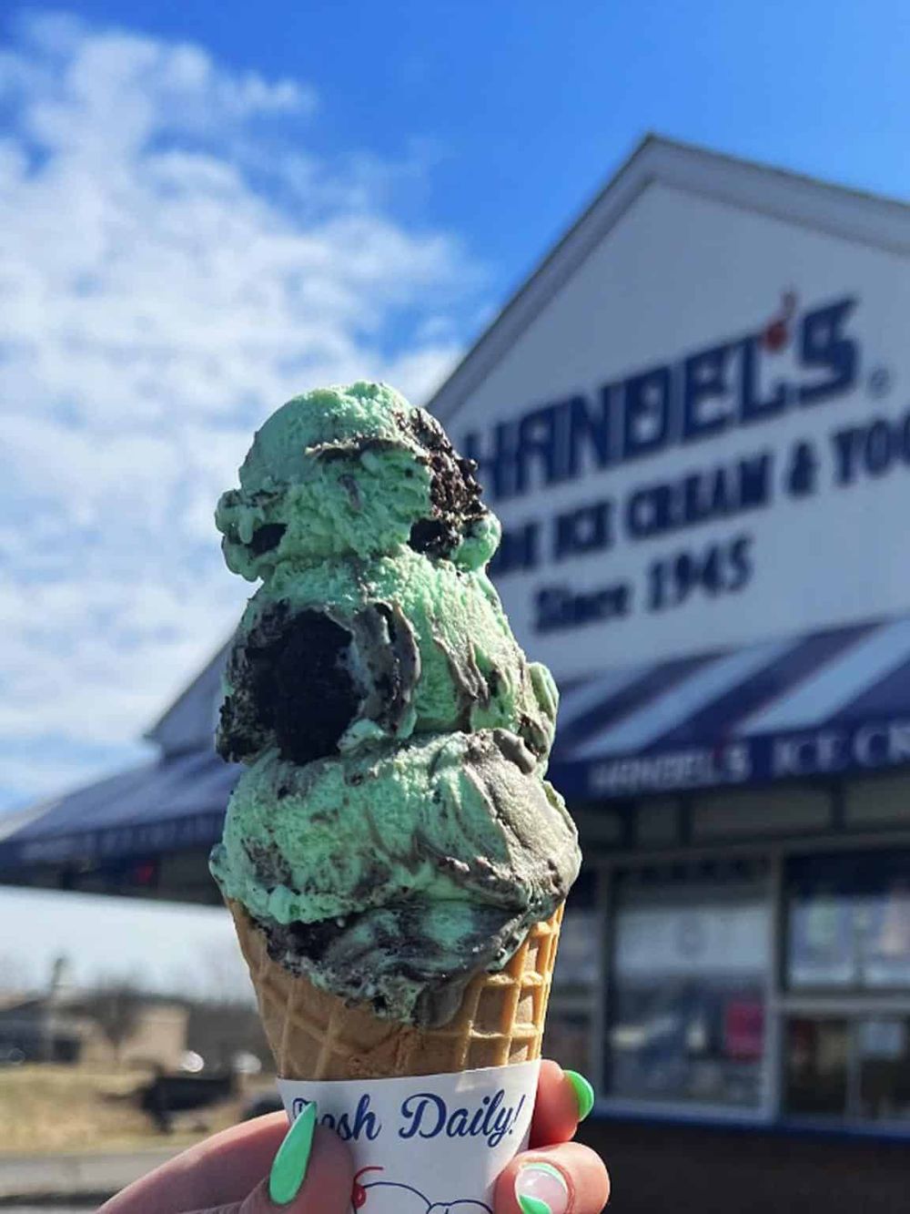 Delicious mint chocolate chip ice cream cone outside of Thrifty's with QuestForDirections sign in the background.