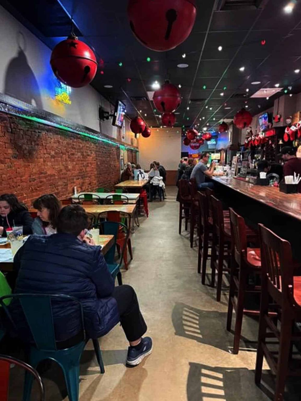 Colorful casual restaurant interior with red lantern décor and bar seating, vibrant atmosphere, and customers enjoying meals.
